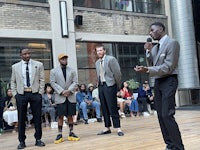 a group of men in suits standing on a stage