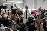 a man in a white suit with his arms raised in the air