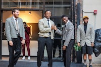 a group of men in suits standing in front of a building